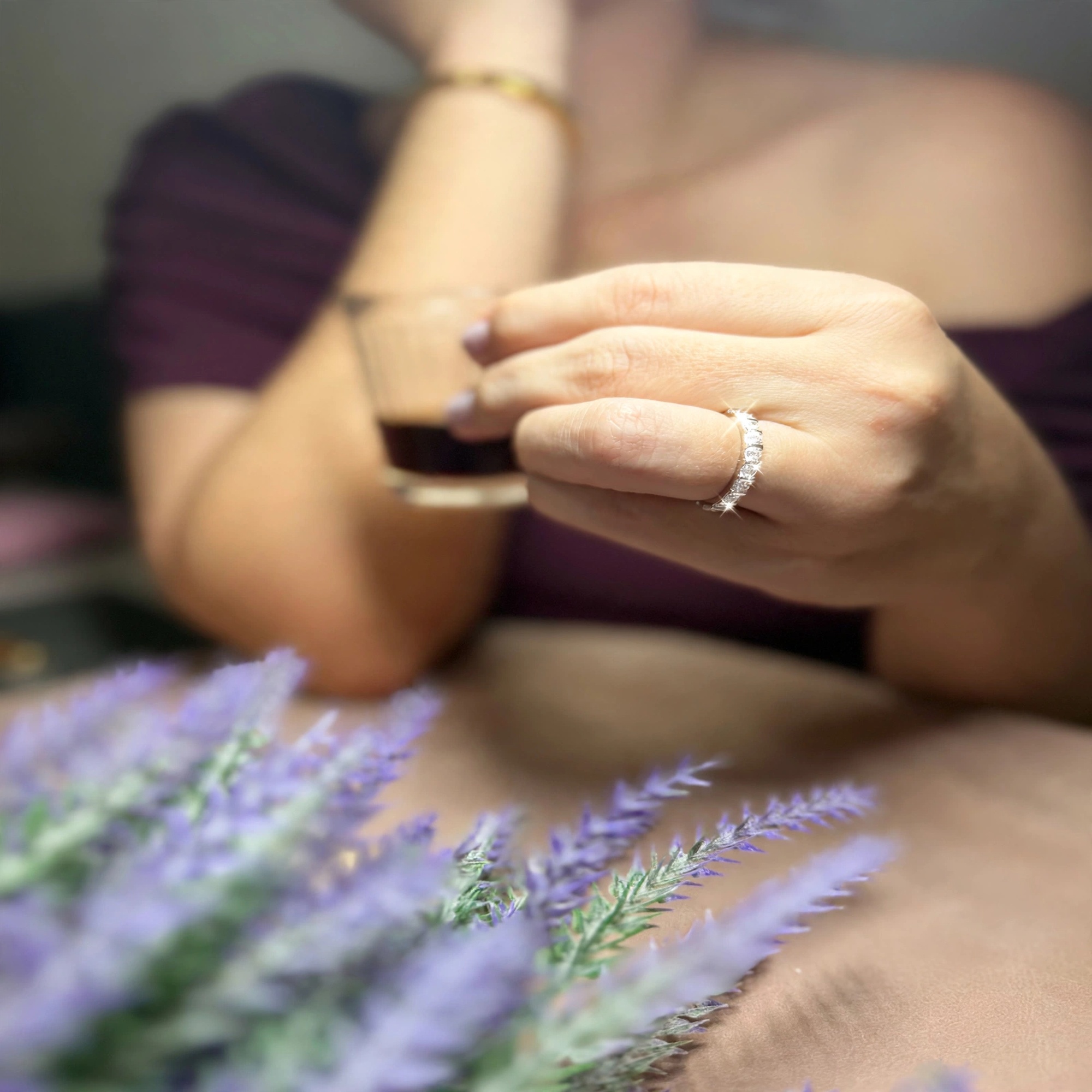 Mão segurando taça de café com anel de zircônias e flores de lavanda à frente