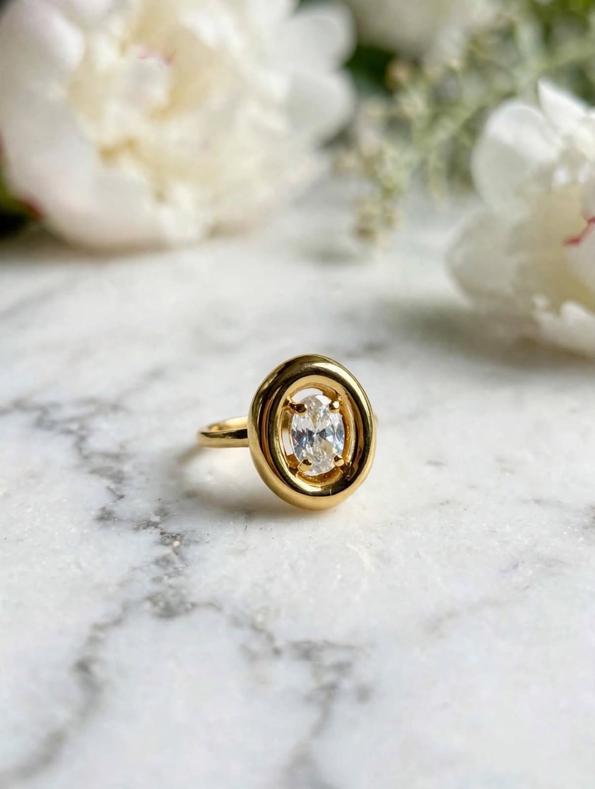 Anel Solitário Peônia, dourado e zircônia oval, sobre mármore